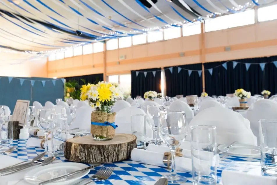 Wedding table decorated with blue table cloth, wooden details, plates, cutlery and wine glasses