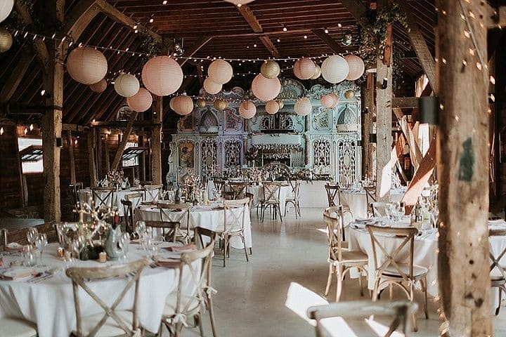 pastel pink and white paper lanterns hanging from the ceiling ove wedding tables.