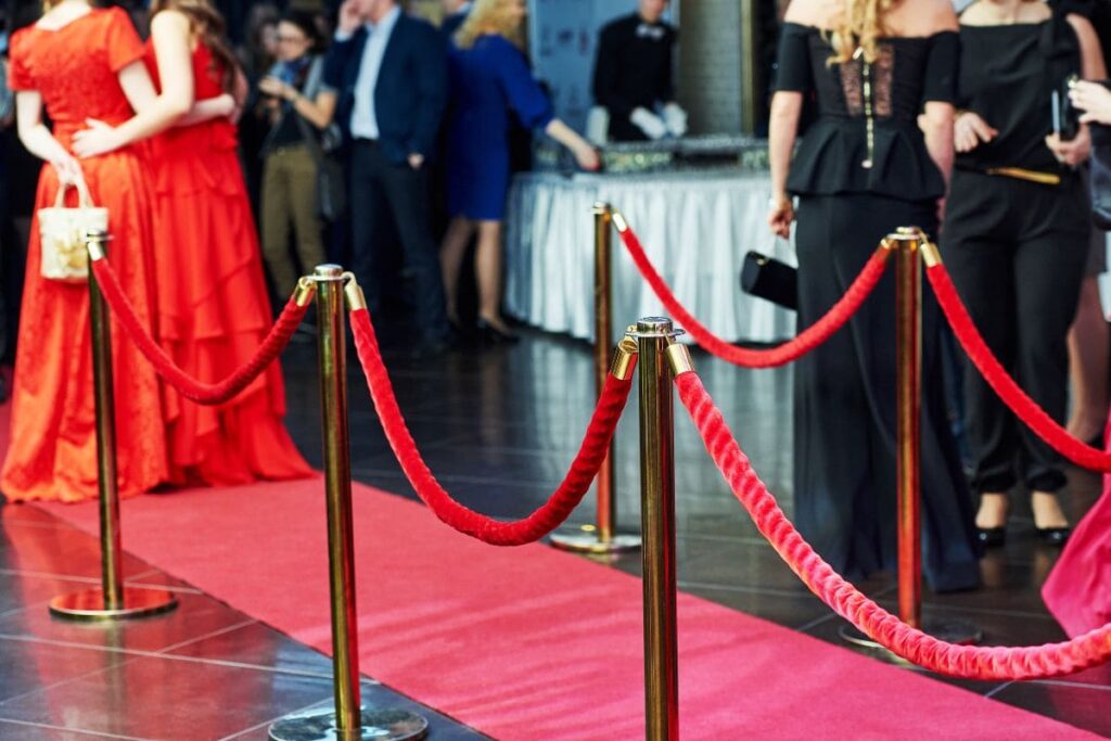 People gathered at a red carpet event dressed in suits and gowns. red carpet in the front of the image. 