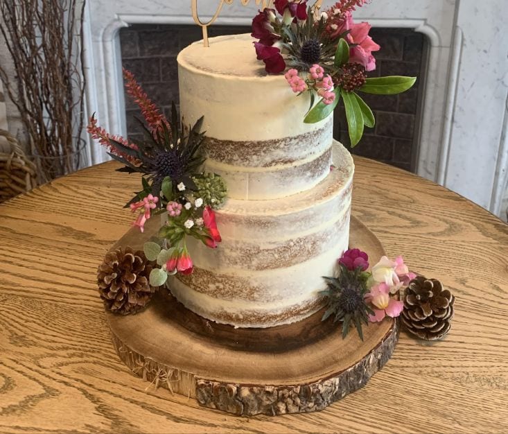 Rustic wedding cake decorated with flowers and pine cones