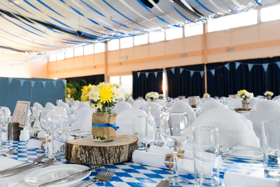 Wedding table decorated with blue table cloth, wooden details, plates, cutlery and wine glasses